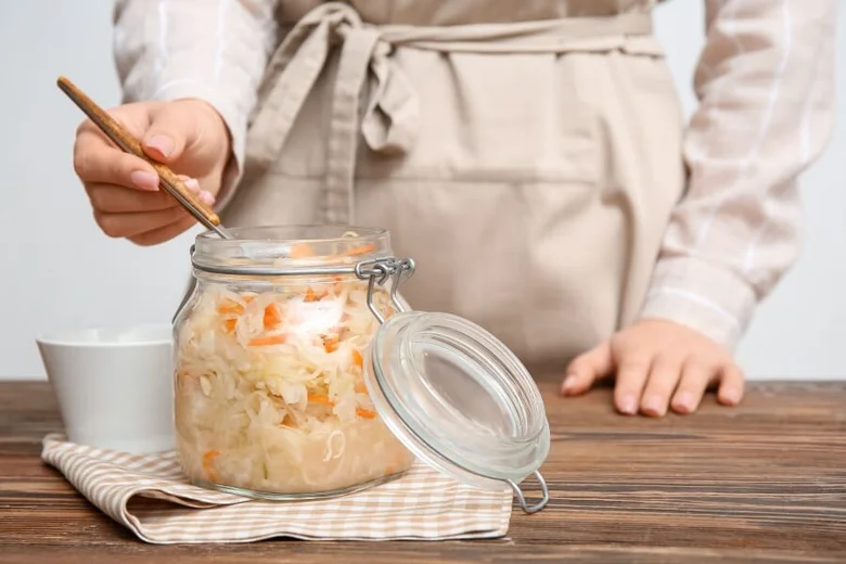 Fermentovaná zelenina v sklenici na stolu.