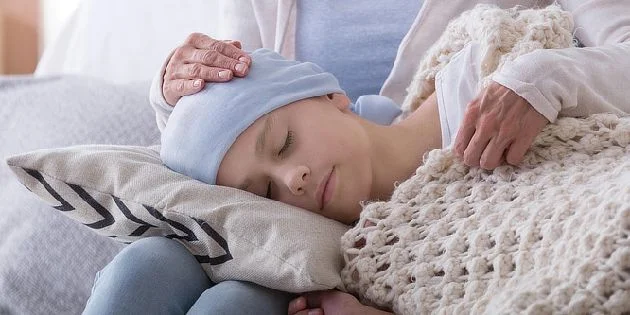 Dítě s bolestí hlavy odpočívá na polštářku pod péčí dospělého.