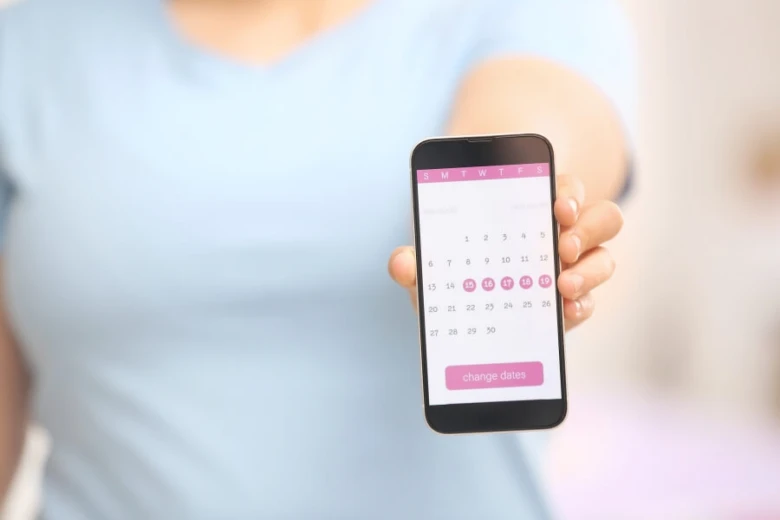 Mobilní telefon s kalendářem menstruačního cyklu ukazuje označené dny.
