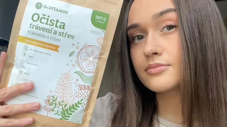 Dívka drží balení přírodního čisticího prášku pro trávení.