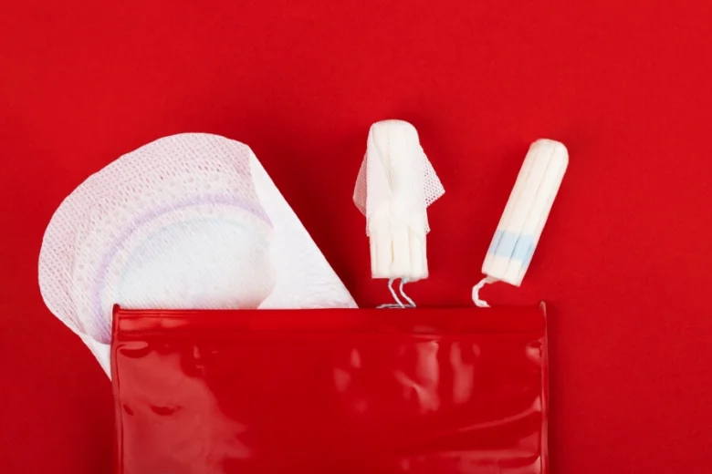 Červená taška s menstruačními vložkami na červeném pozadí.