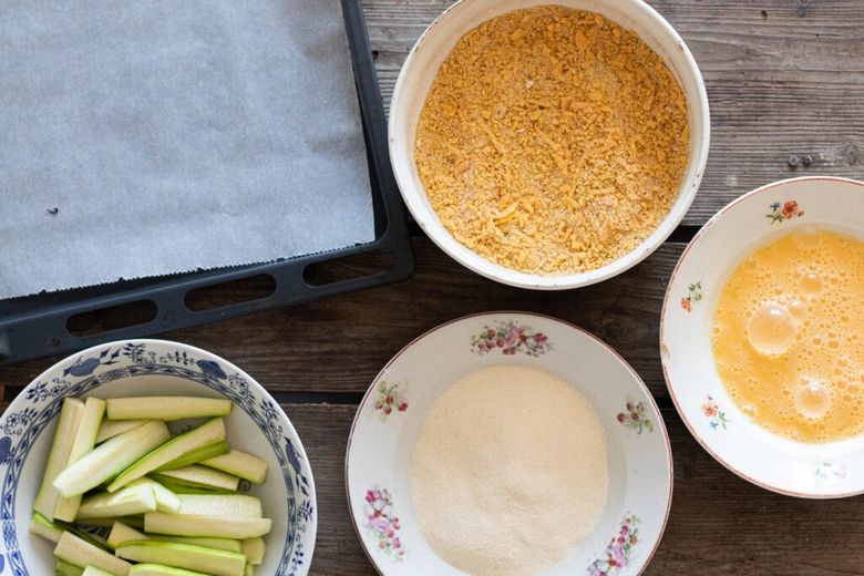 Ingredience pro křupavou cuketu: strouhanka, vejce, mouka a nakrájená cuketa.