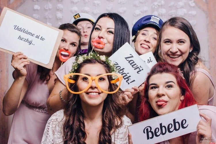 Skupina žen se smíchem v fotoboothu na svatbě s nápisy