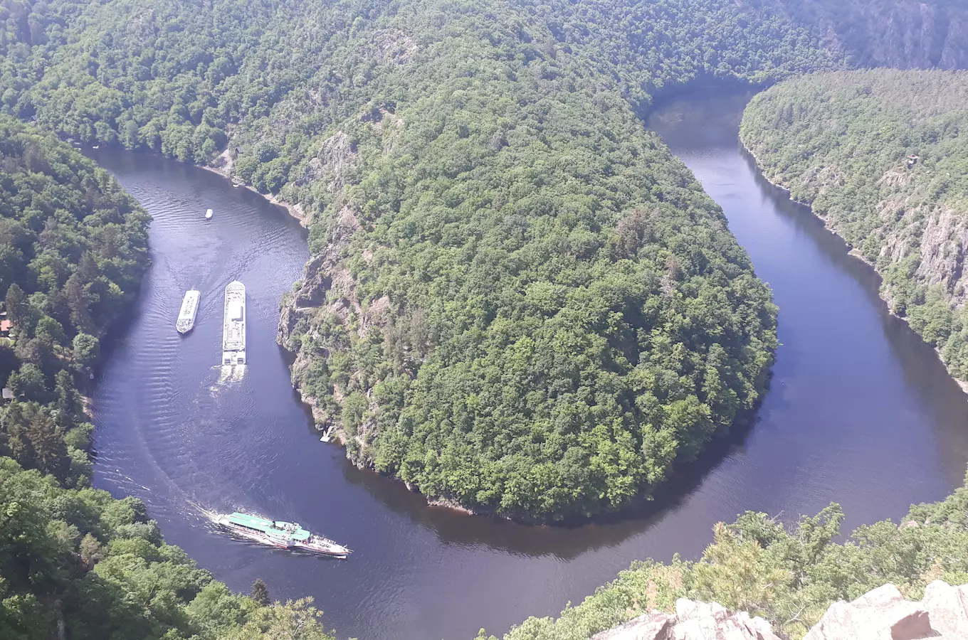 Pohled na řeku s loděmi v zátoce obklopené lesy